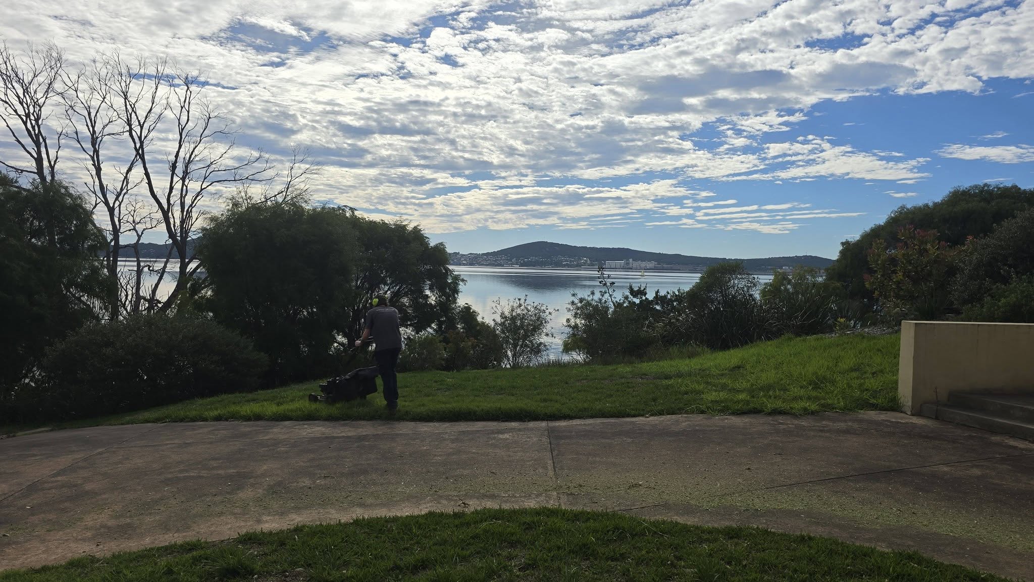 Mowing a lawn by the water near Albany
